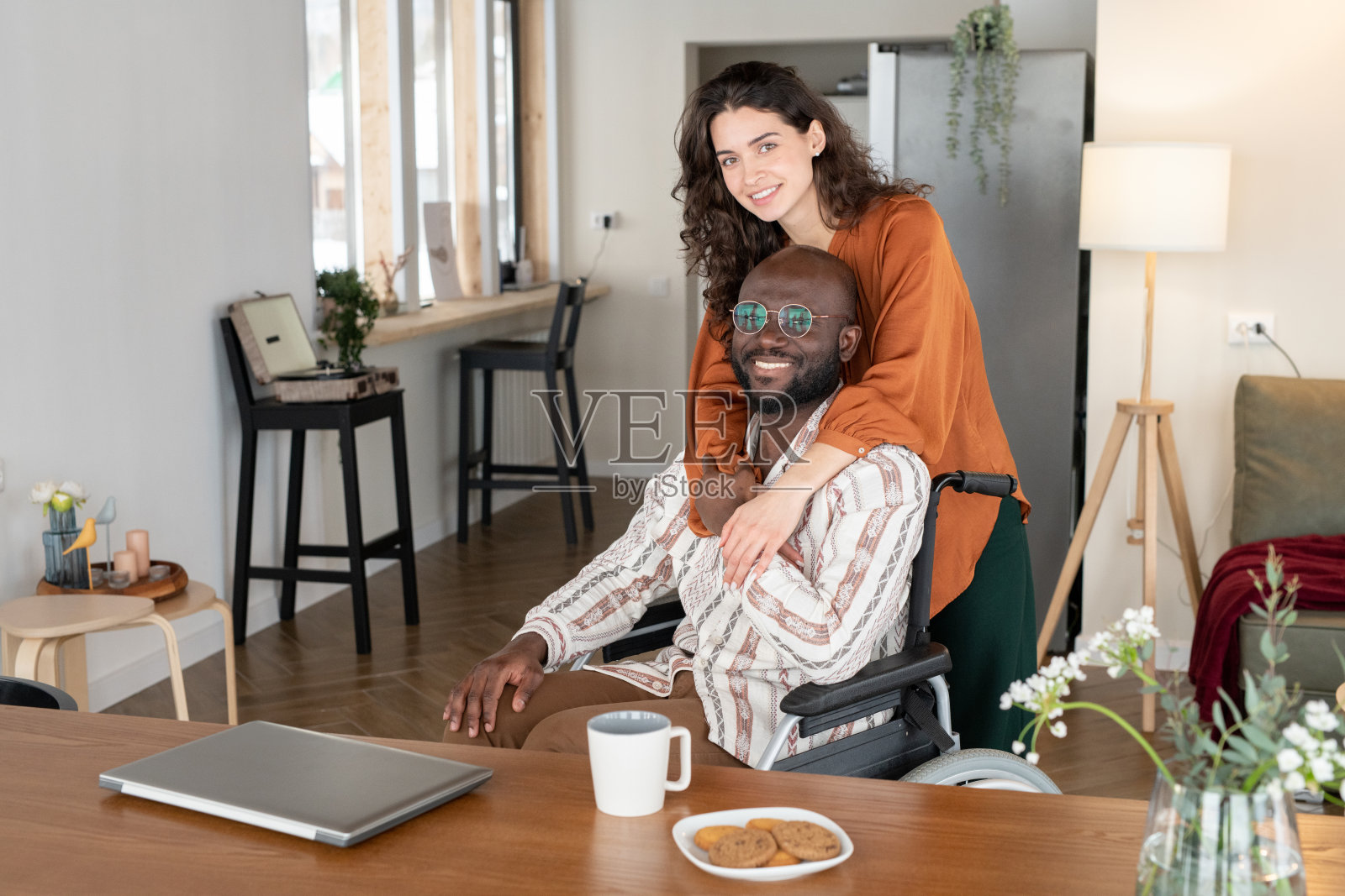 快乐的年轻女性拥抱着残疾的男人，同时看着镜头照片摄影图片