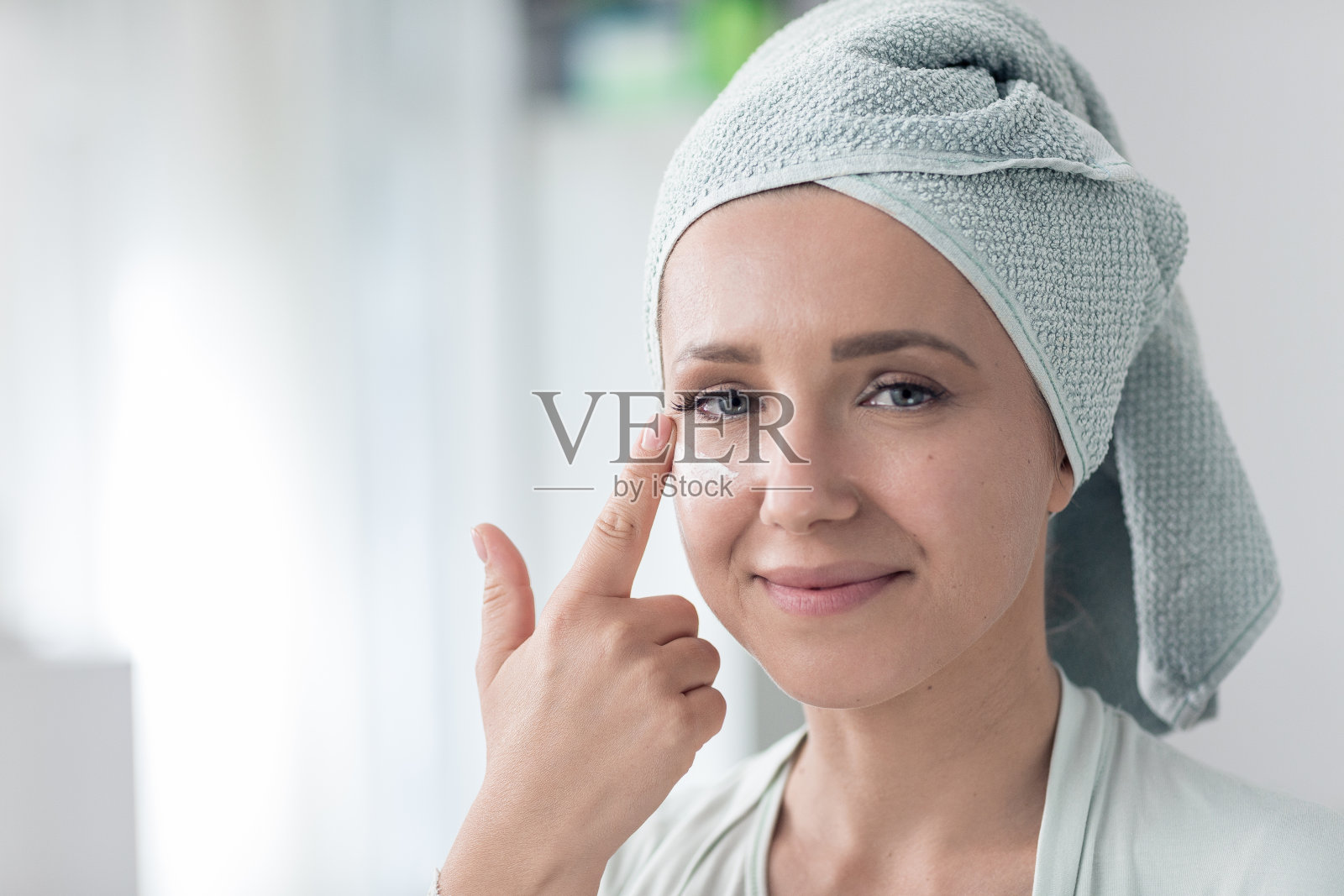 美丽的女人在沐浴后涂面霜照片摄影图片