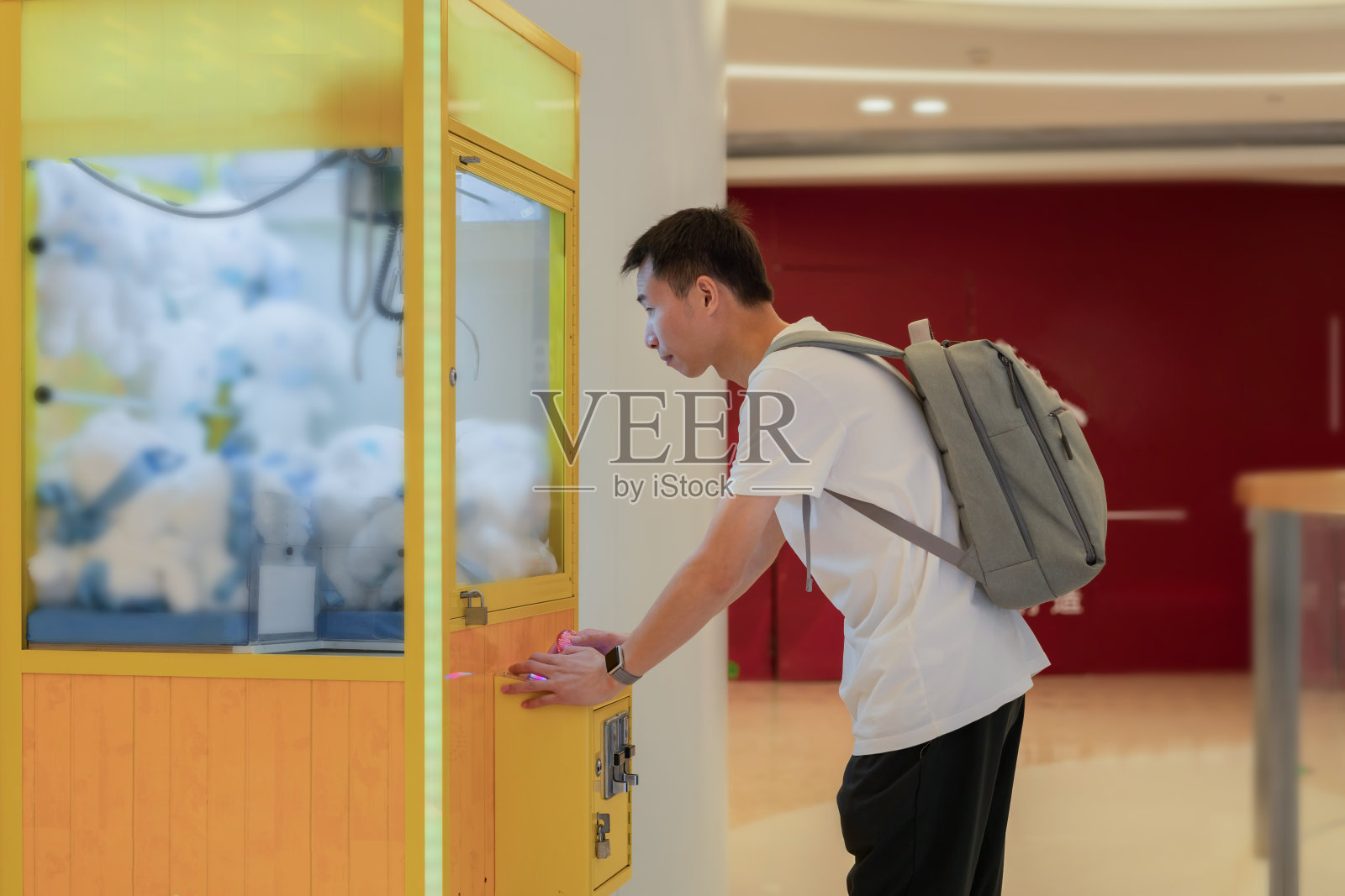 一个亚洲男人在玩抓娃娃机照片摄影图片