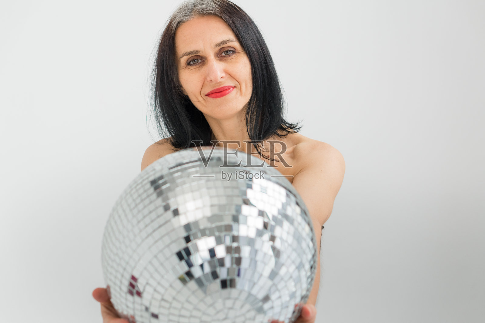 工作室照片中年妇女开始灰色的头发穿黑色的衣服和银色的迪斯科球在白色的背景上，中年性感的女士，快乐的生活概念照片摄影图片
