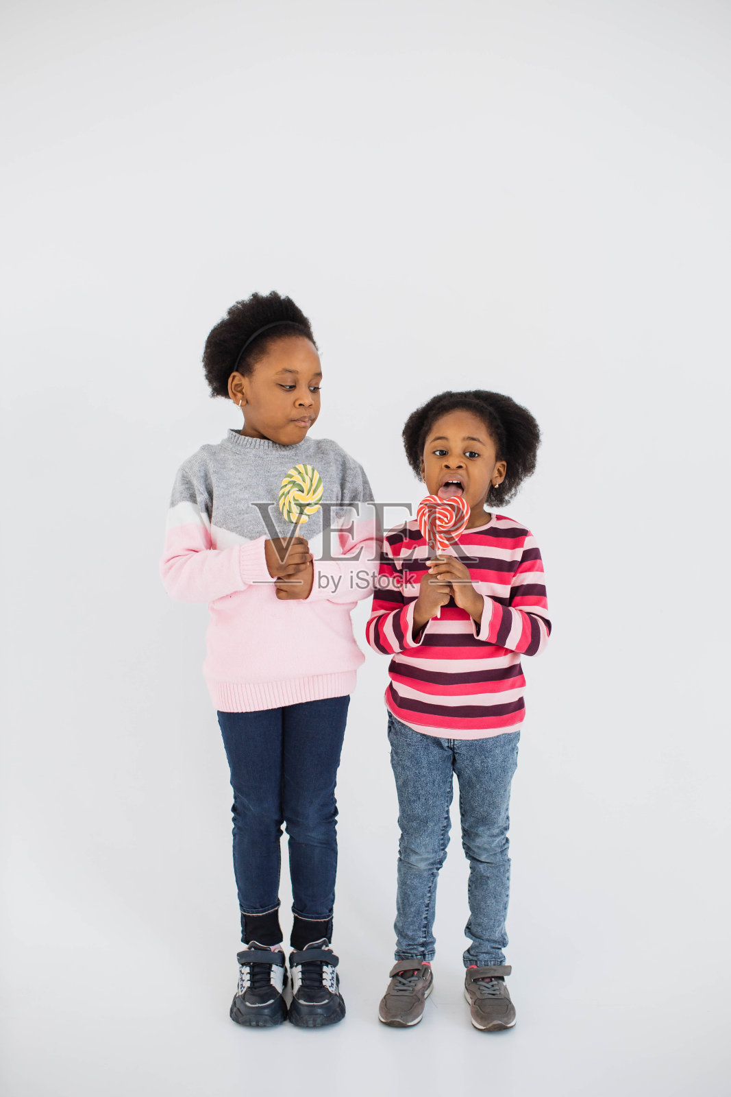 非裔美国姐妹在演播室里舔棒棒糖照片摄影图片