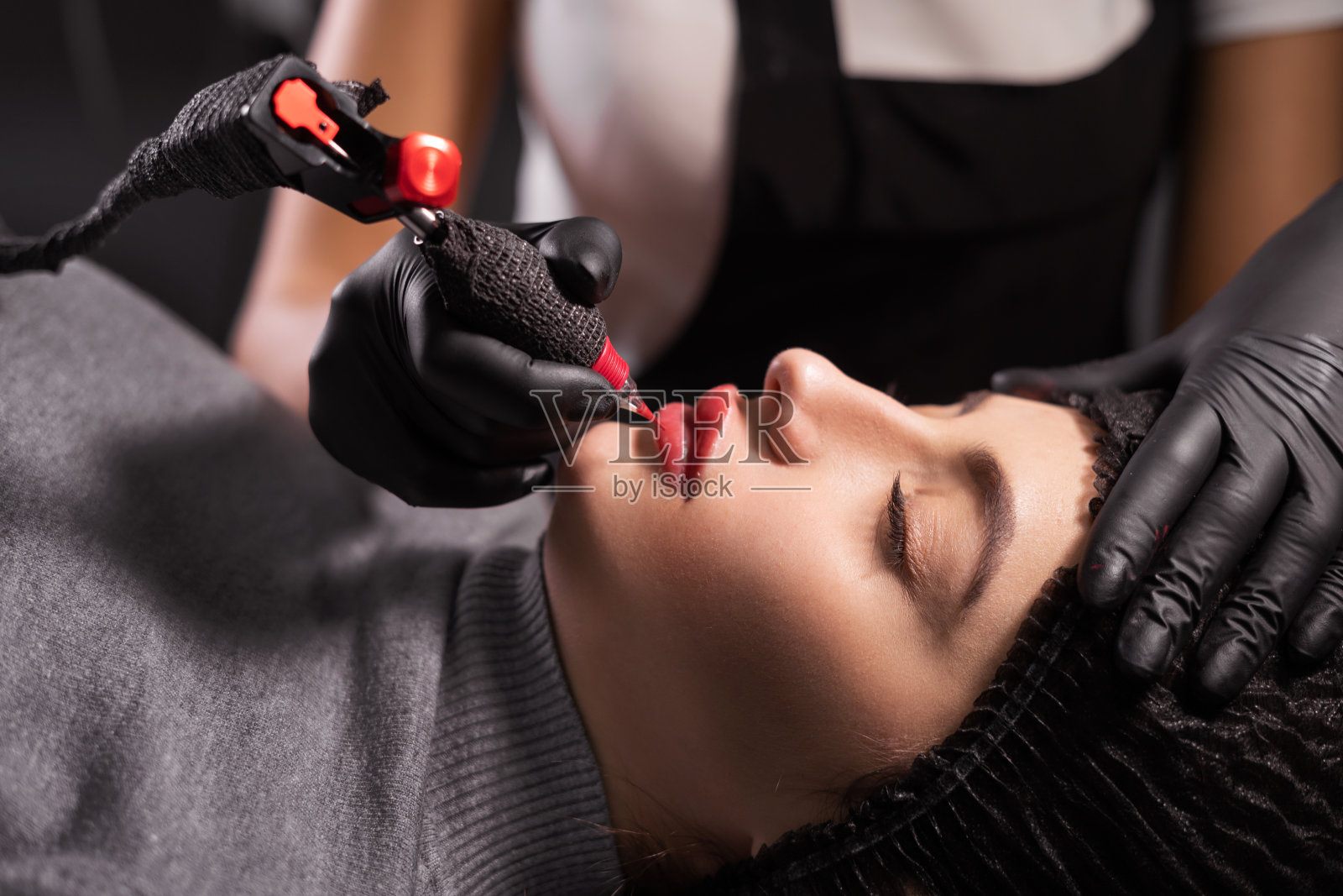 大师在唇妆时的肖像。脸上有纹身，嘴唇有微色素沉着。专业面部microblading。照片摄影图片