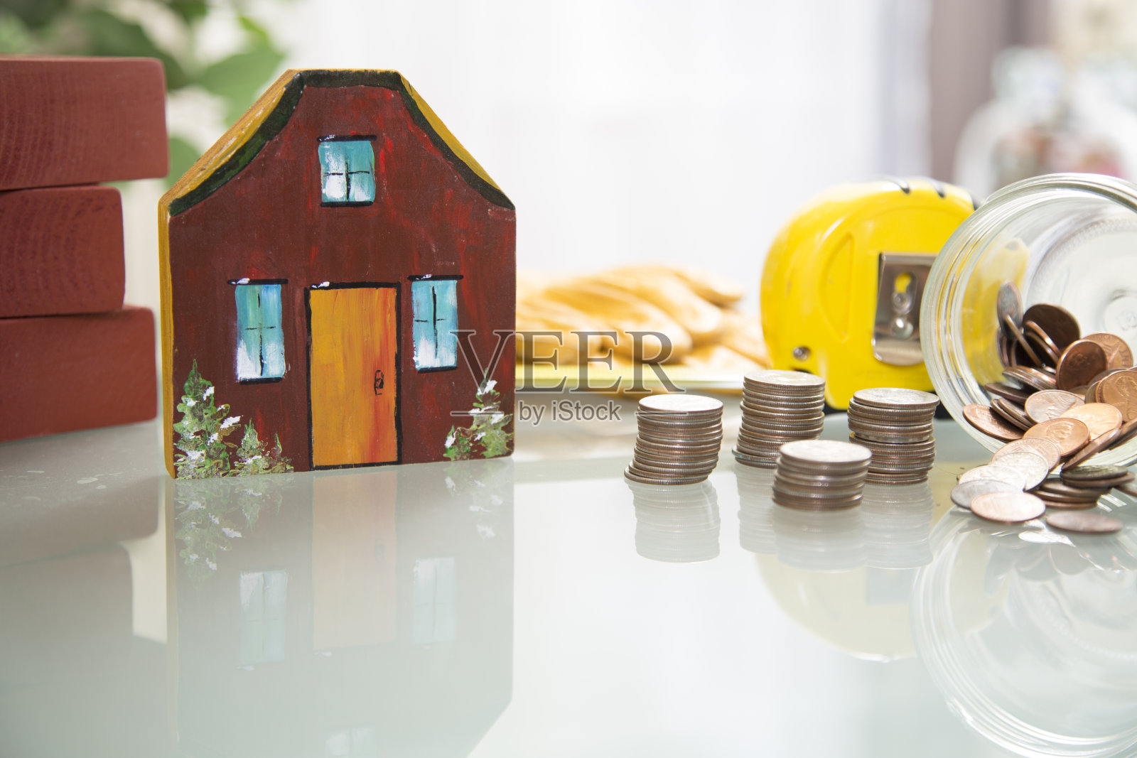 新屋建筑。漆过的木块构成了一所房子。装着硬币的玻璃罐可以用来买房子。照片摄影图片