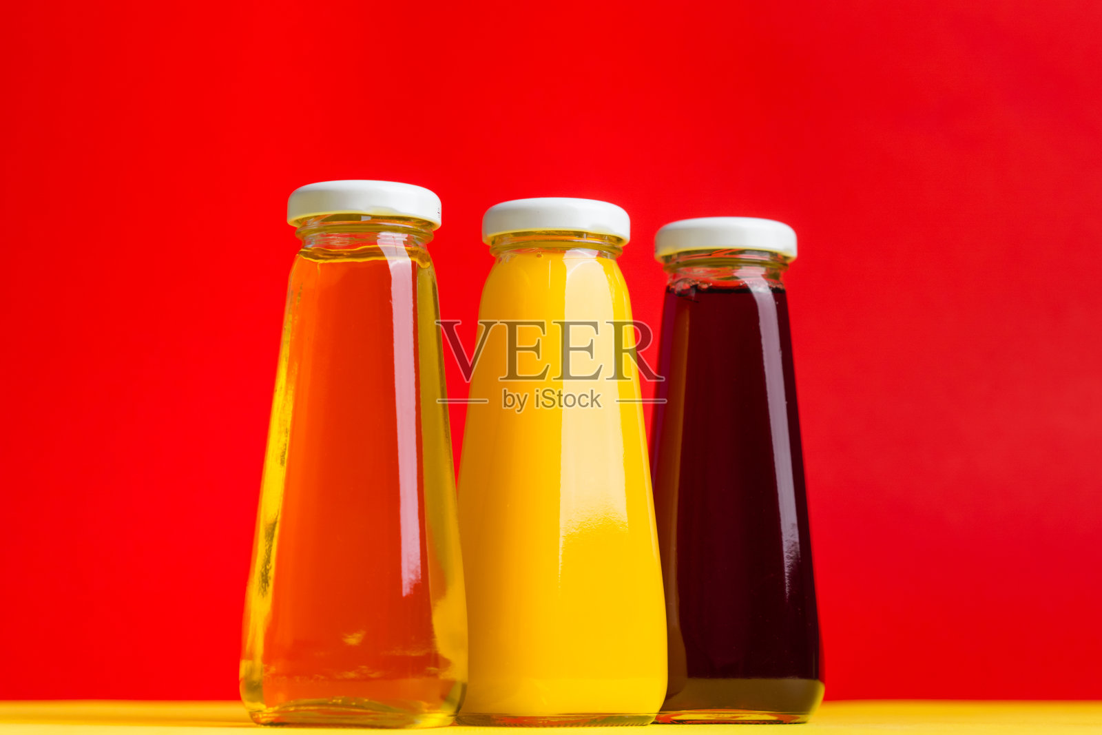 黄色和红色的液体健康饮料在黄色和红色的背景上。橙色苹果樱桃照片摄影图片