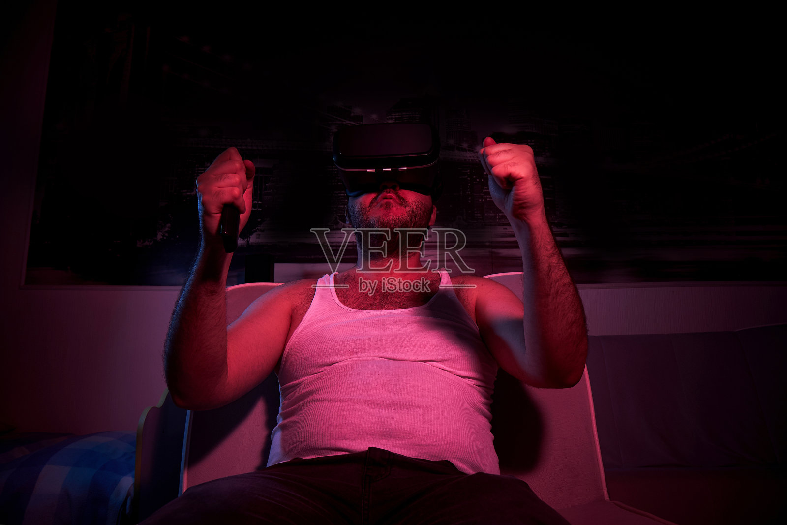 40岁的肥胖男子戴着VR眼镜看电视，表现出各种情绪，生气。懒惰的中年男人照片摄影图片