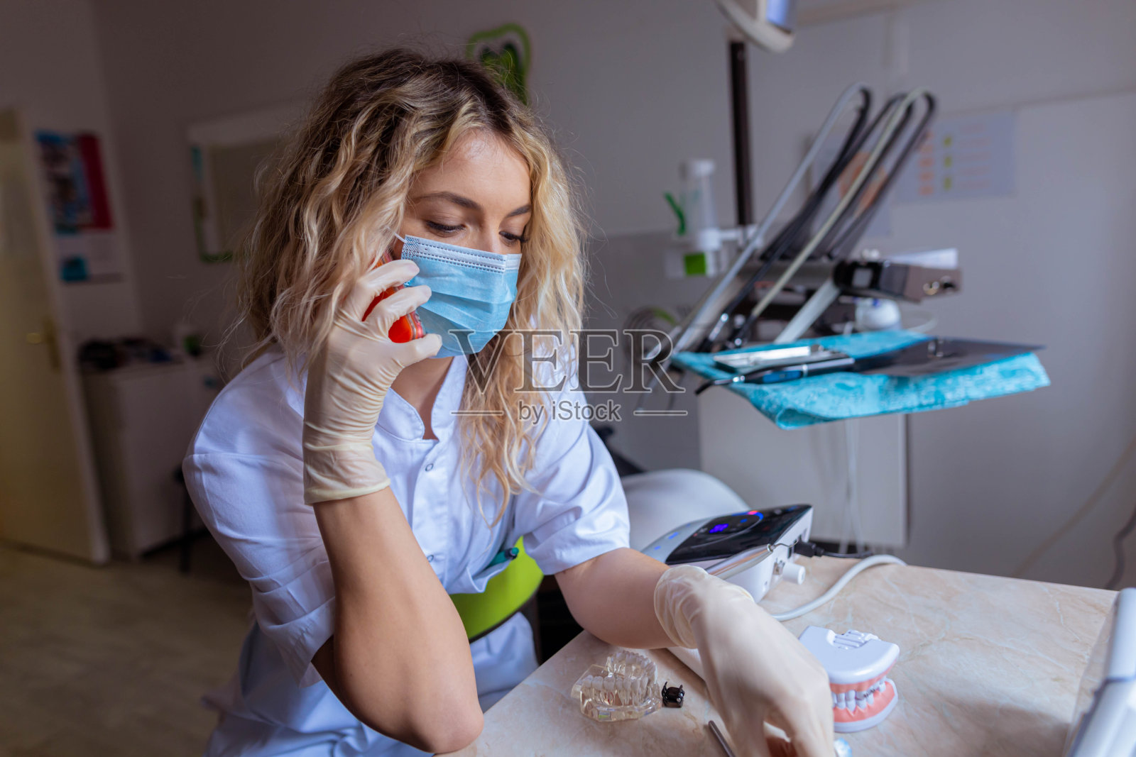 白人女性牙科助理，在牙医的主持下用手机通话照片摄影图片