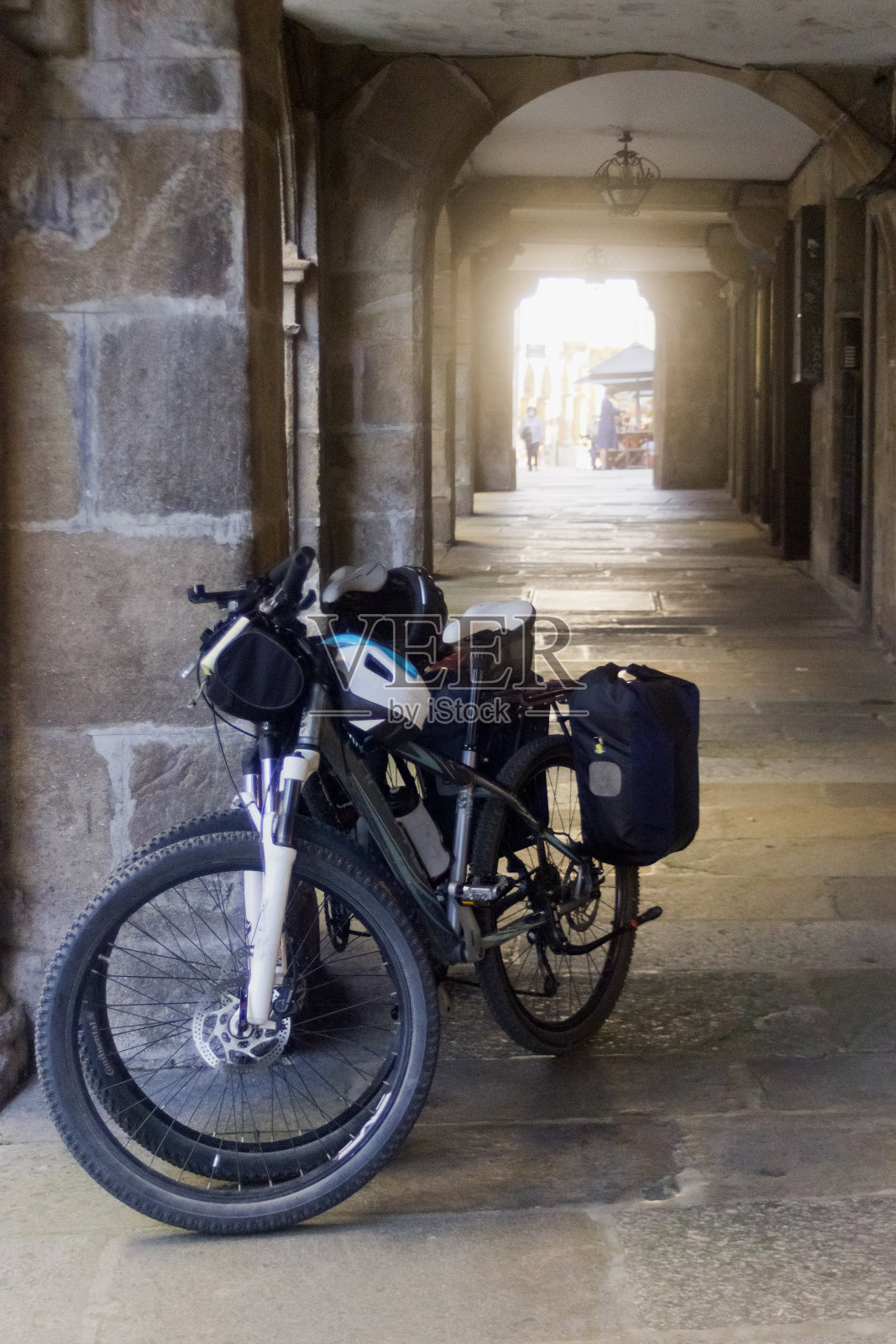 在圣地亚哥德孔波斯特拉老城，两辆自行车斜倚在拱廊步行街上。照片摄影图片