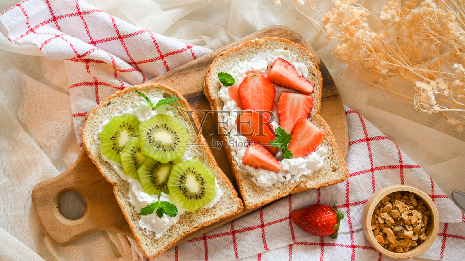 木盘上的草莓吐司和猕猴桃吐司。照片摄影图片