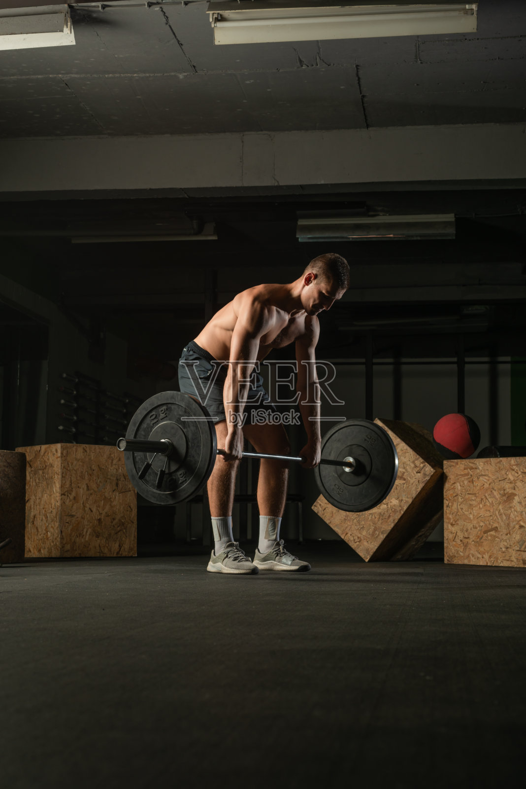 健康强壮的赤膊运动员做深蹲。硬核交叉健身的概念。照片摄影图片