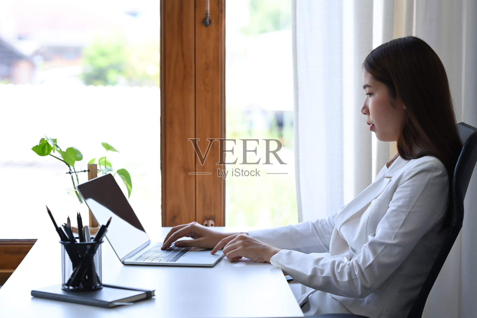 侧视图亚洲工作妇女观看在线网络研讨会笔记本电脑。照片摄影图片