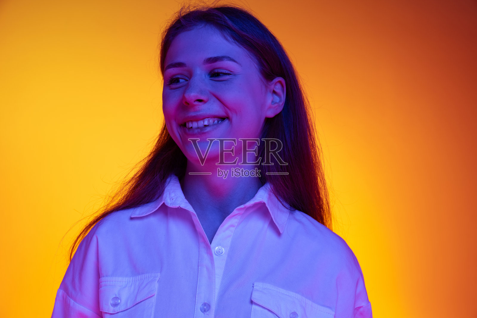 微笑。年轻美丽的感性的女孩在白色衬衫孤立的橙色背景霓虹灯，滤镜的肖像。情感、时尚、青春的概念照片摄影图片