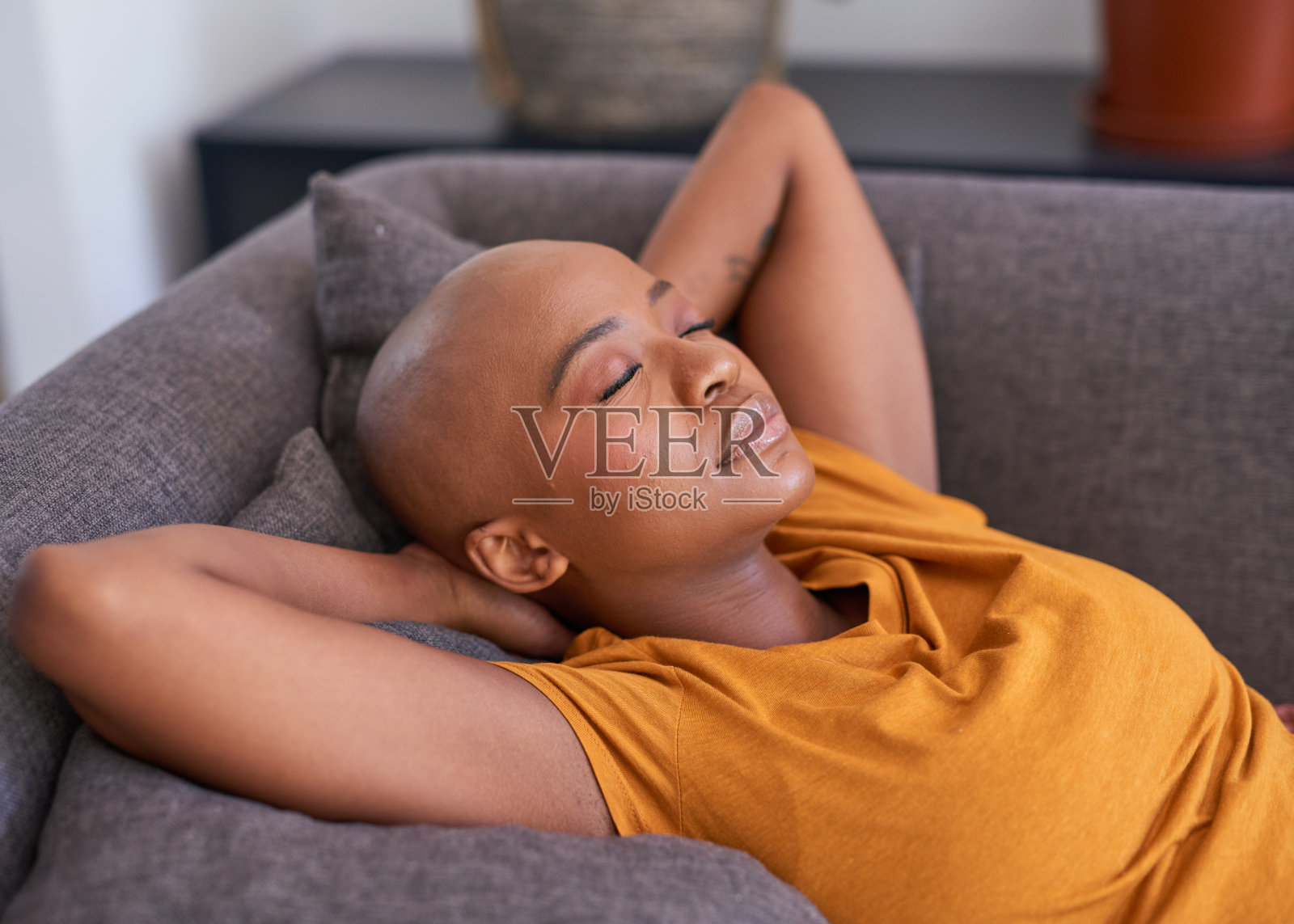 一个年轻女子躺在沙发上，双臂枕在脑后照片摄影图片