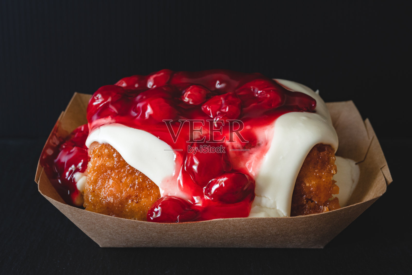 新鲜烘焙的樱桃霜桂皮卷接近黑色的背景照片摄影图片