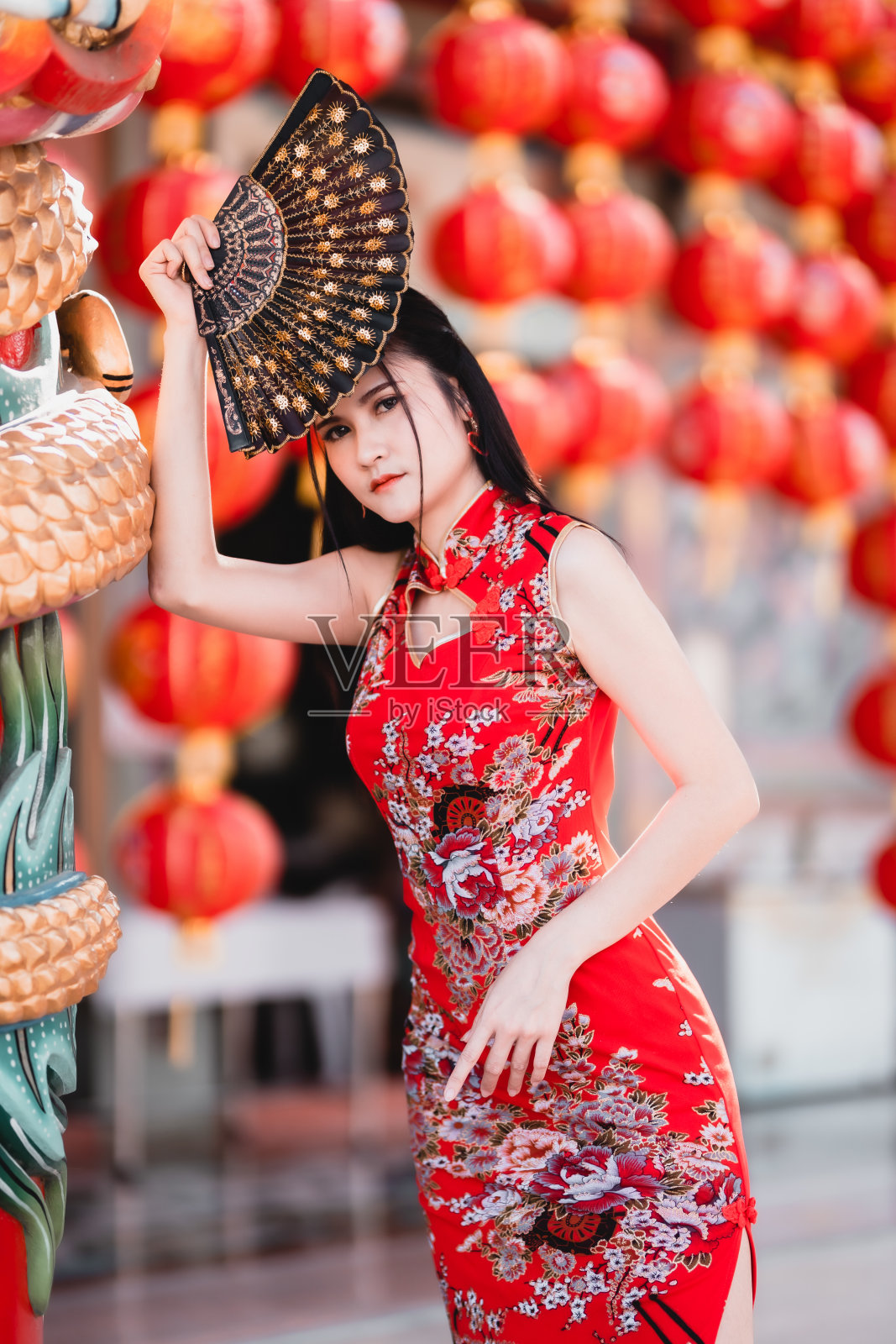 肖像美丽的微笑亚洲年轻女子穿着红色的中国传统旗袍装饰，在泰国的中国祠堂举行中国春节扇宁照片摄影图片