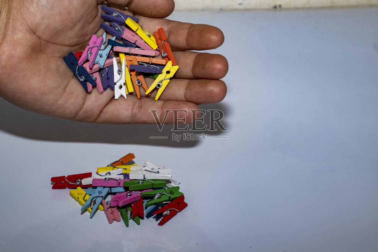 手拿迷你彩色衣夹，装饰。孤立的白色背景。空间,复制模板。手拿迷你彩色衣夹，装饰。孤立的白色背景。照片摄影图片