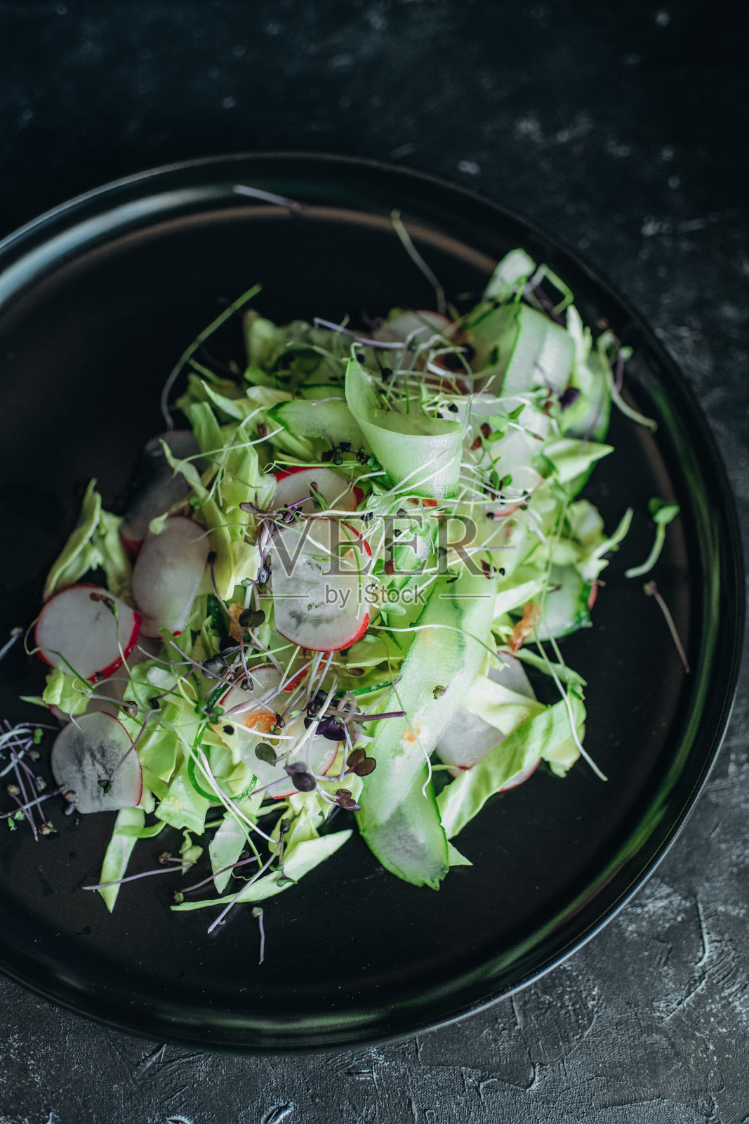 黑色盘子里的新鲜蔬菜沙拉和绿叶蔬菜照片摄影图片
