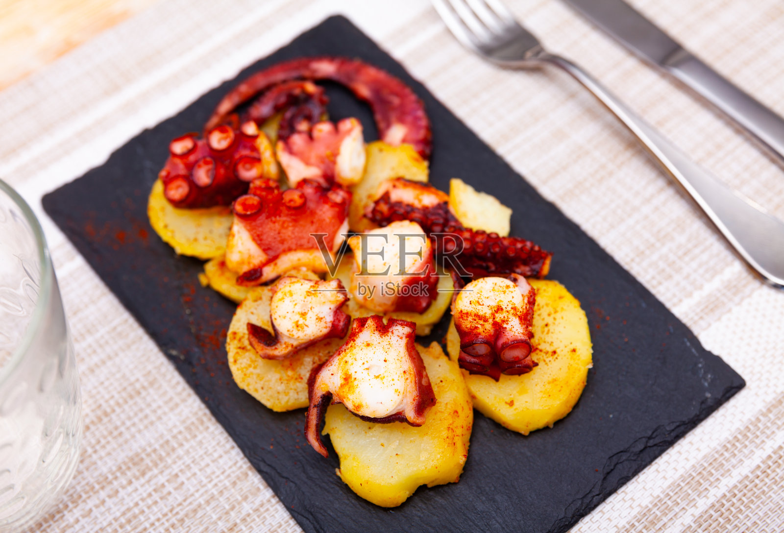 煮章鱼触手，烟熏辣椒粉和土豆放在石板上照片摄影图片