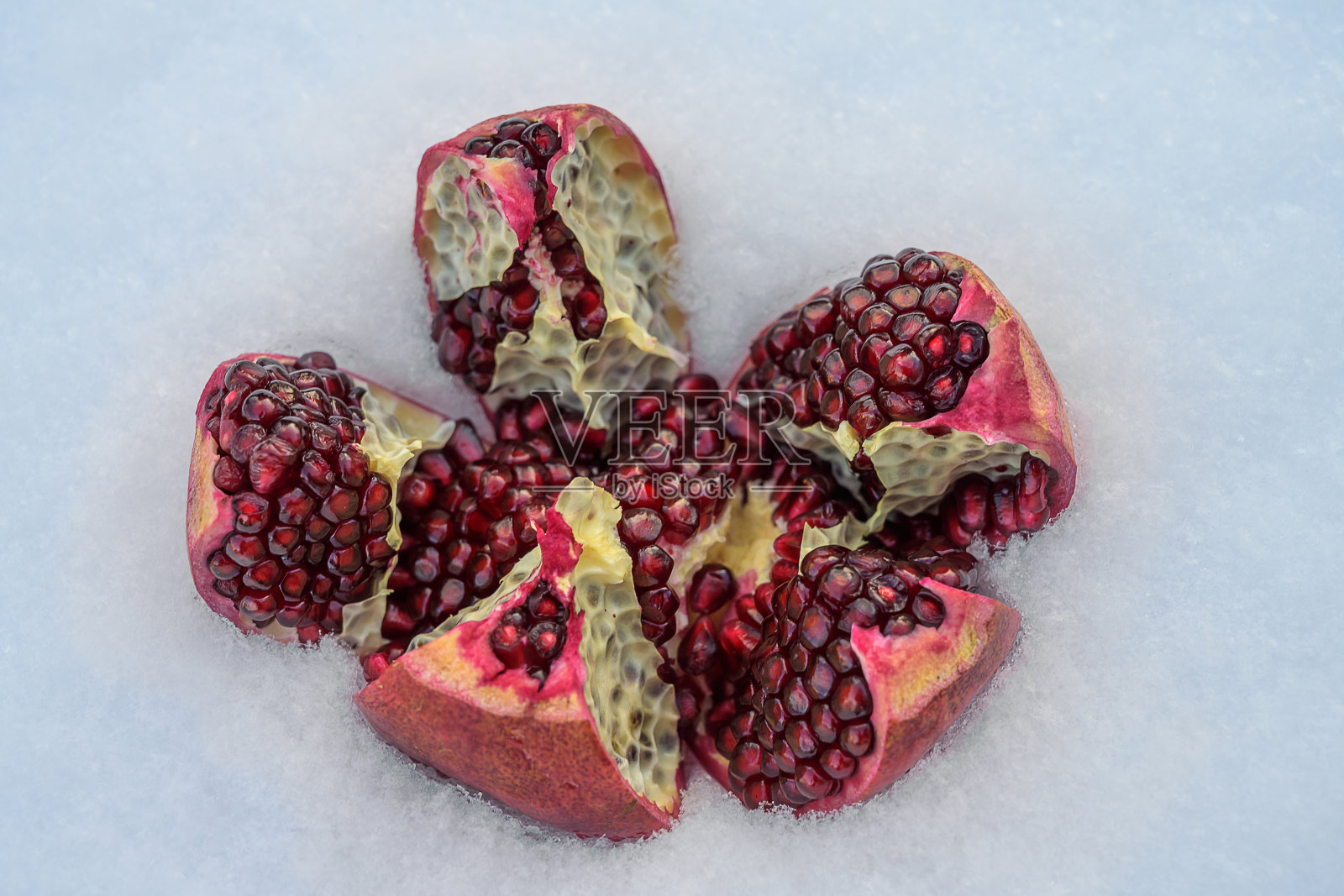 雪地里的一片片成熟的石榴。特写镜头。照片摄影图片