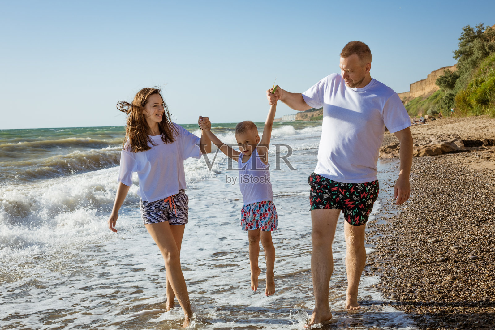 幸福的一家人在海边散步照片摄影图片