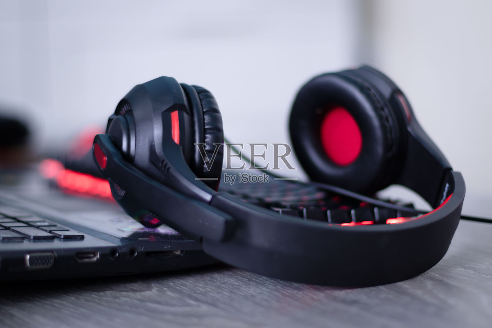 键盘上有红色细节的耳机，还有红色发光按钮。耳机用于玩，工作，听音乐。照片摄影图片