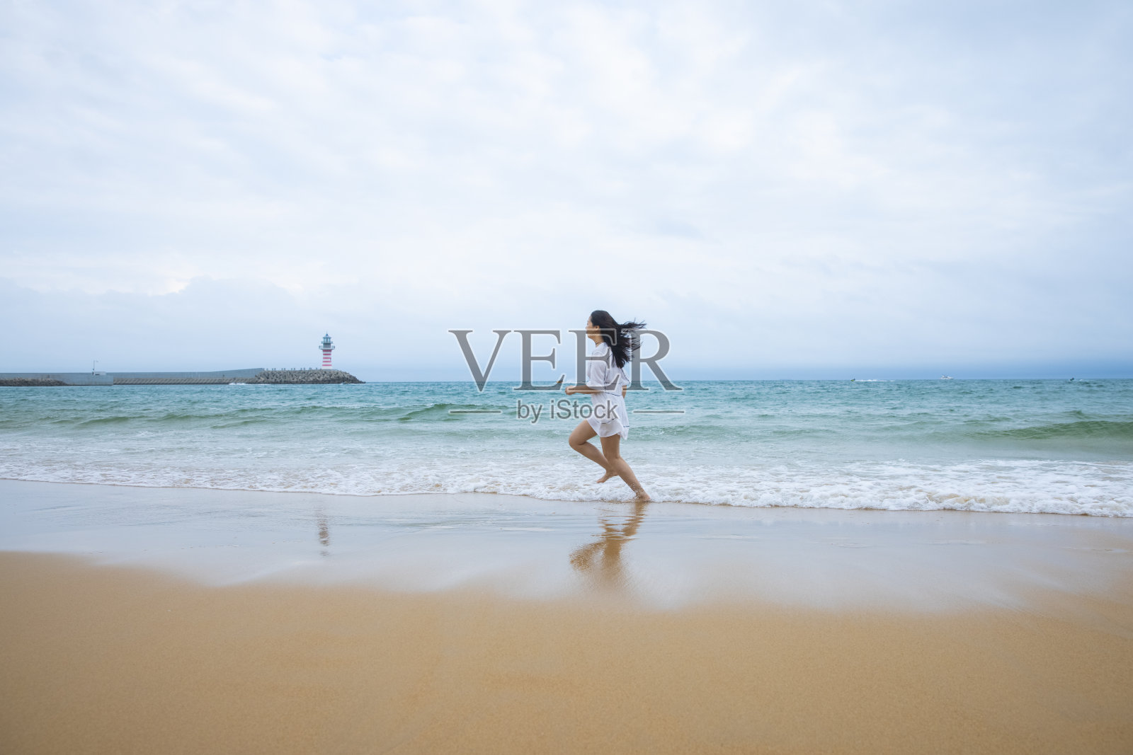 年轻女子在沙滩上奔跑照片摄影图片