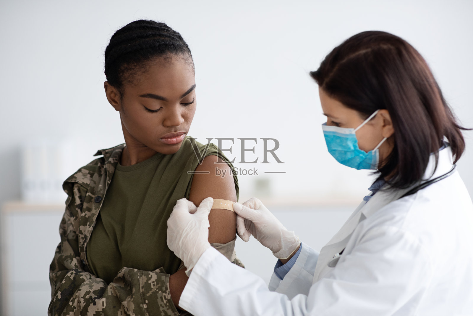 女医生注射后在黑色军士肩上贴膏药照片摄影图片