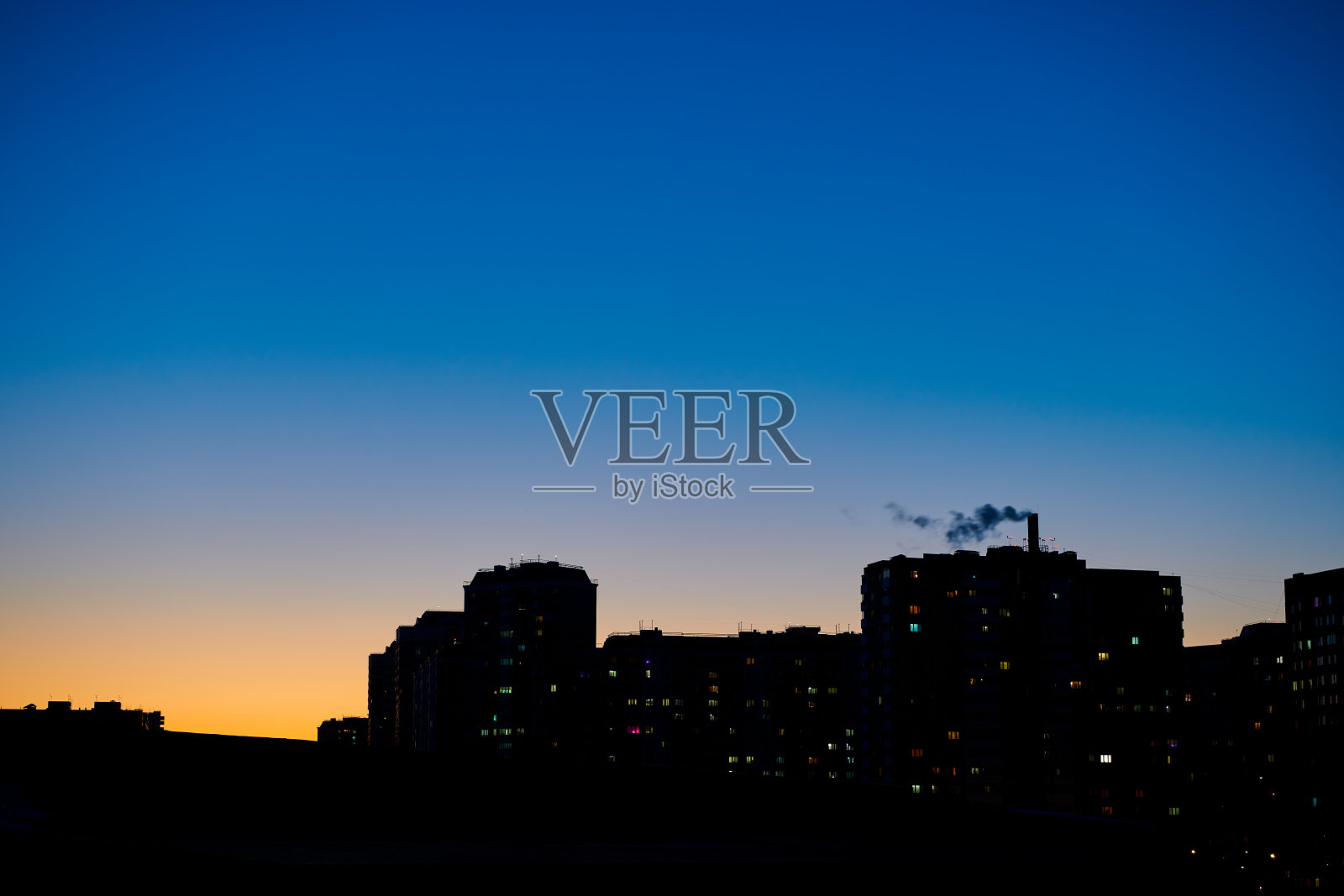 城市建筑的黑色轮廓映衬在晴朗的夜晚深蓝色的天空下。傍晚天空渐黄渐蓝。晚上在城市。夜晚的城市。城市景观背景。照片摄影图片