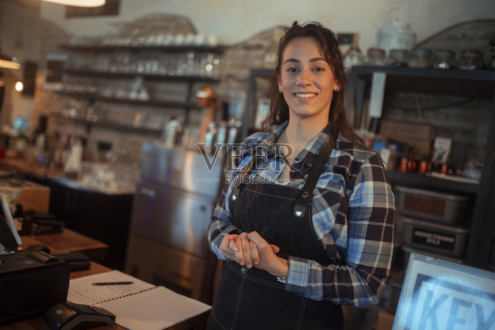 一名微笑的女服务员站在一家咖啡店里。照片摄影图片