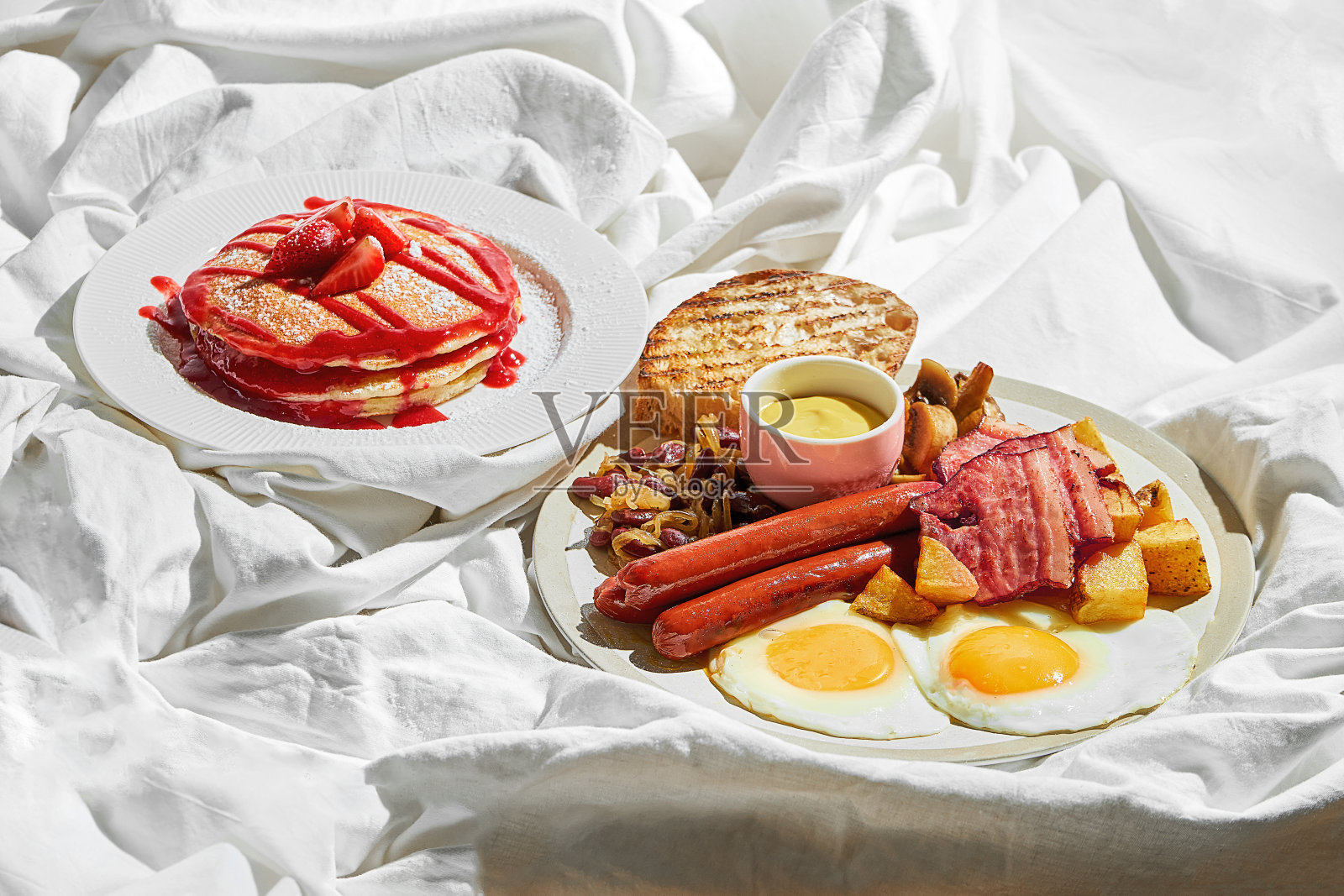 英式早餐薄煎饼，铺在白床单上。艰难的光照片摄影图片