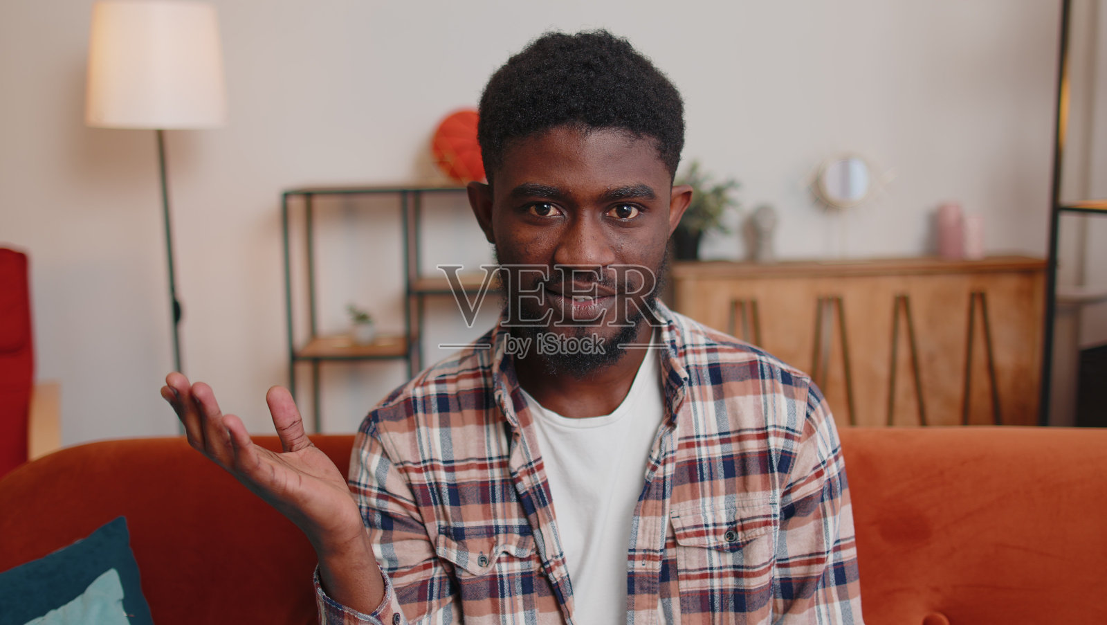 男人坐在家里的沙发上，看着摄像机，和朋友或父母进行视频电话会议照片摄影图片