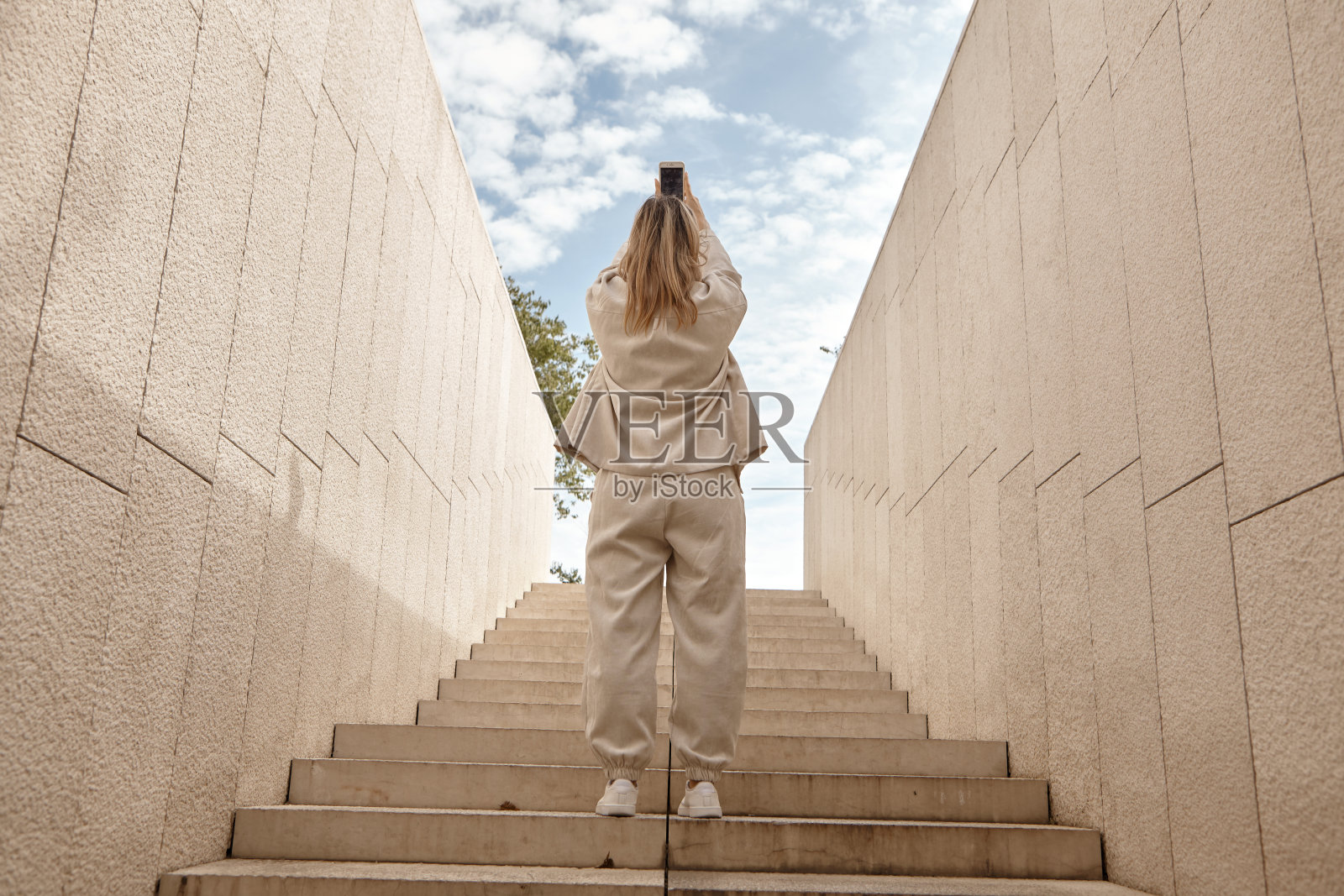 一名女子正在用手机拍摄天空照片摄影图片