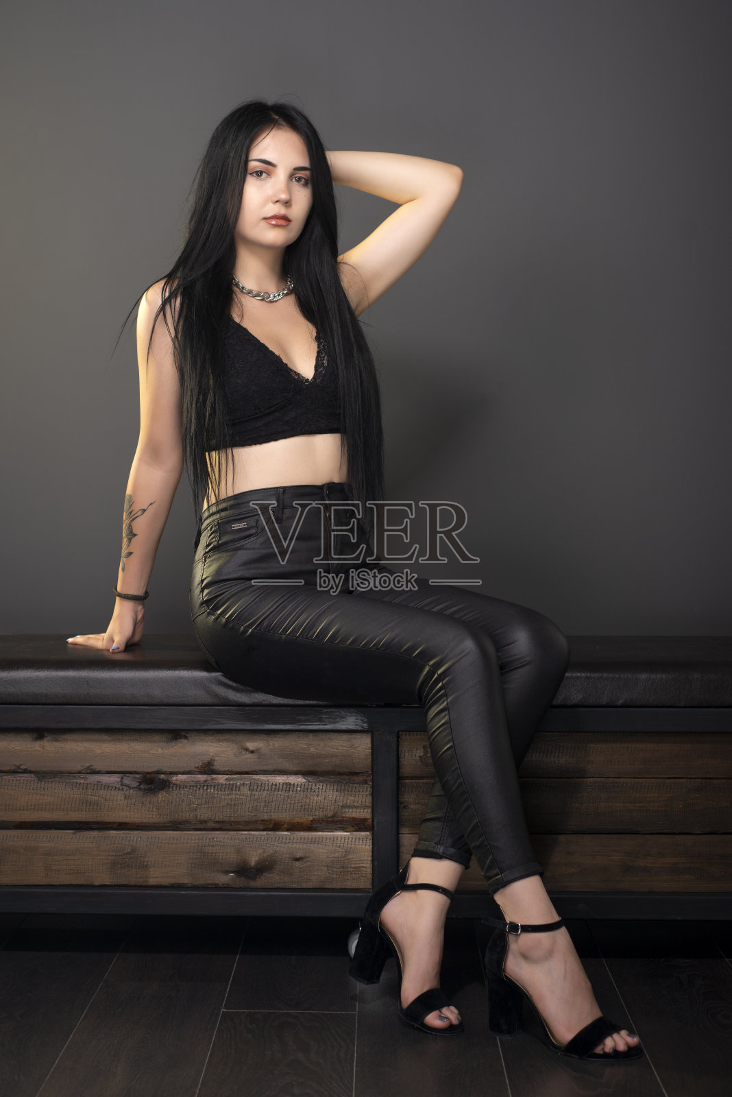 美丽的年轻模特女孩坐在工作室摆姿势，看着相机。照片摄影图片