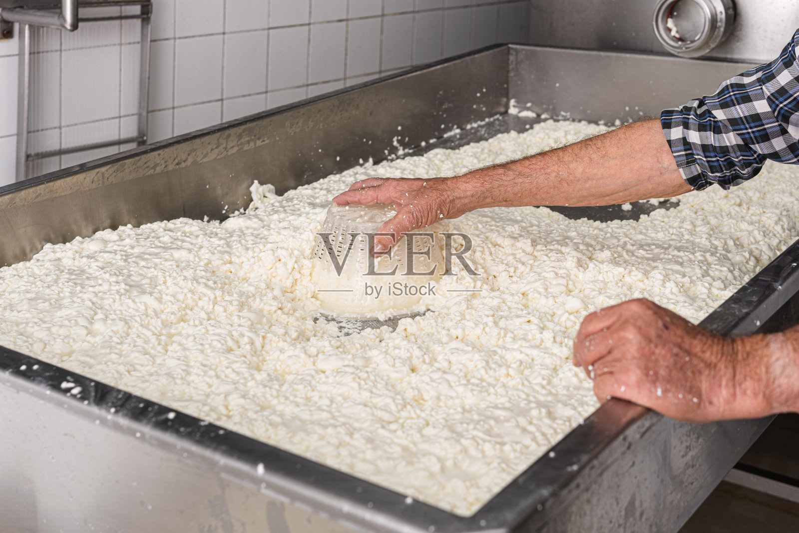 老人用筛子搅凝乳，把它与乳清分开照片摄影图片