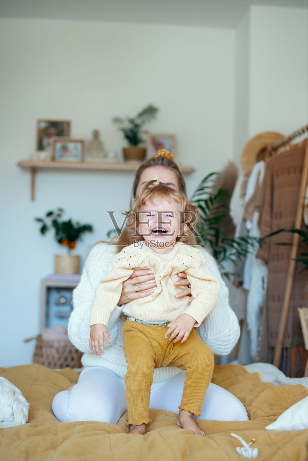年轻漂亮的妈妈在家里和宝贝女儿玩耍。照片摄影图片