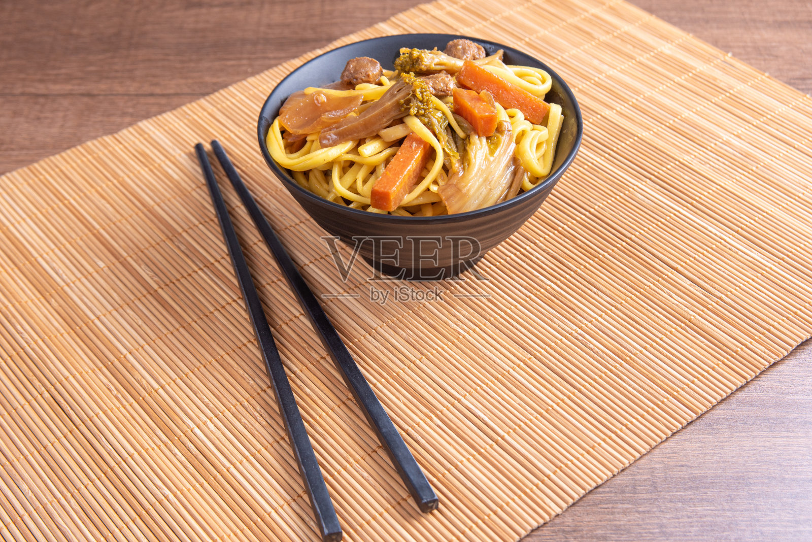 素食食品，素食日式炒面，用筷子放在碗里，在竹垫上，在木头上，选择性的重点。照片摄影图片