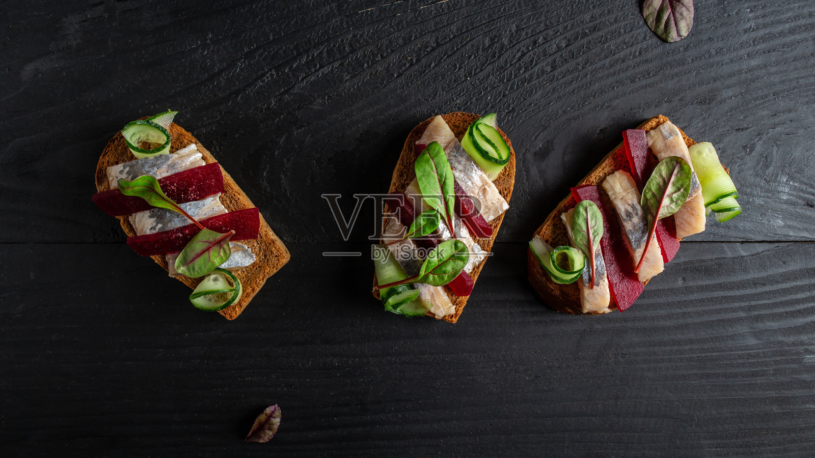 鲱鱼角。三文治，腌鲱鱼，甜菜根片，青瓜，洋葱和微绿色的烤面包。北欧美食。传统的丹麦三明治。俯视图照片摄影图片