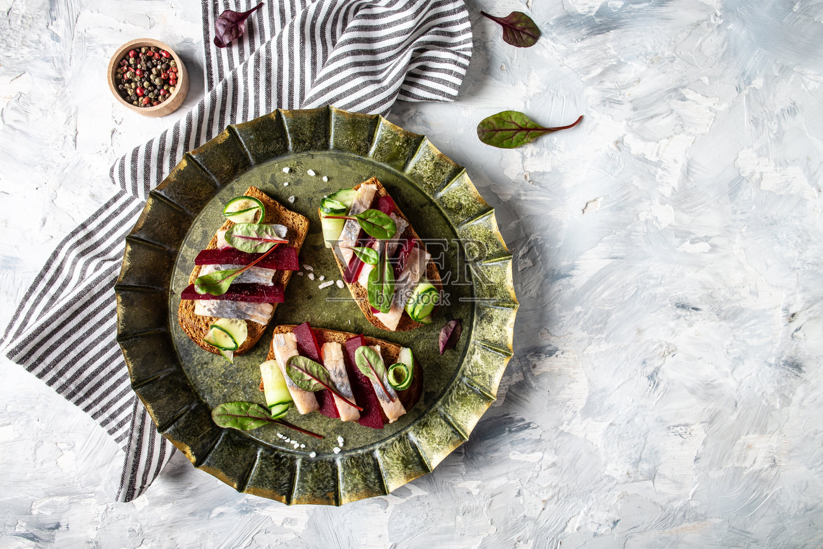 鲱鱼角。三文治，腌鲱鱼，甜菜根片，青瓜，洋葱和微绿色的烤面包。北欧美食。传统的丹麦三明治。俯视图照片摄影图片