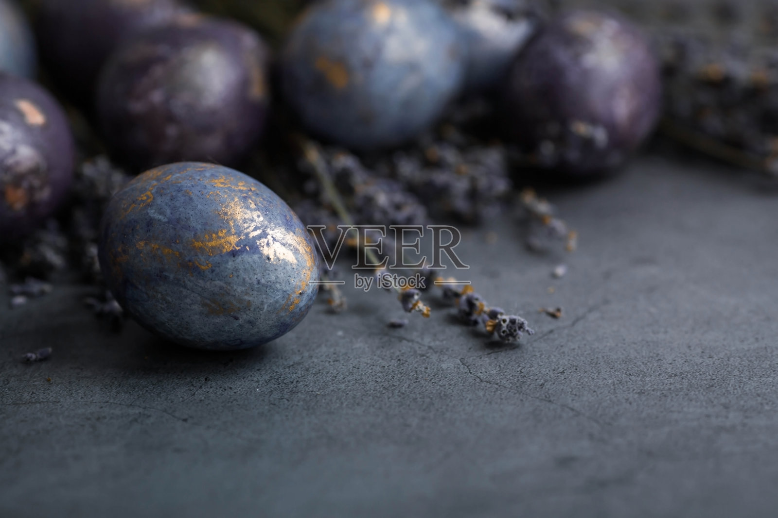 复活节卡片上有副本的文字。紫色，蓝色和金色鸡蛋与薰衣草在黑暗的背景。2022年的紫色趋势是非常相关的。天然染料karkade茶。前视图。照片摄影图片