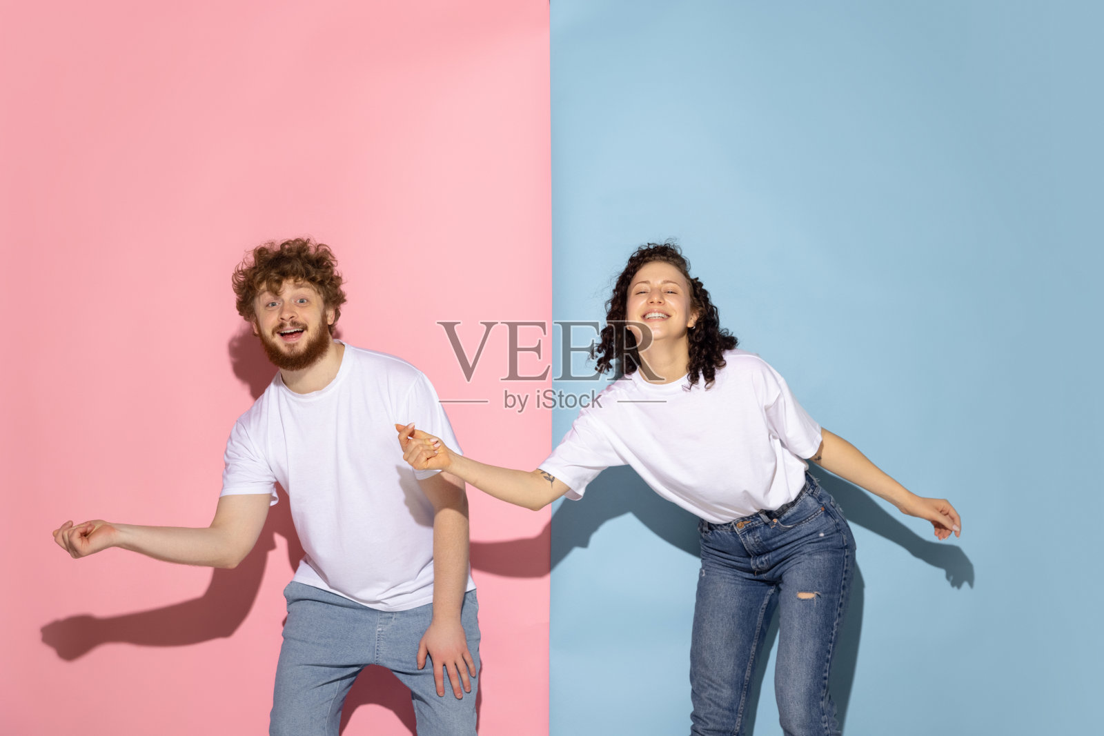 情感夫妇年轻有趣和快乐的男人和女孩跳舞嘻哈在工作室的蓝色和粉红色流行的颜色背景。照片摄影图片