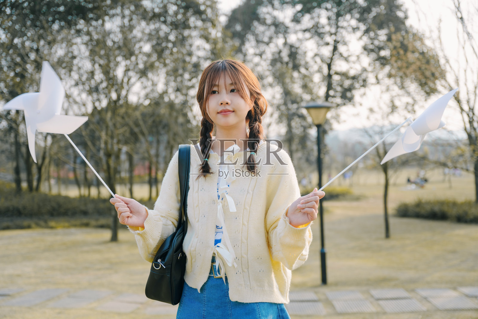 一个美丽的亚洲女孩和一个纸风车在一个阳光明媚的日子在草地上照片摄影图片