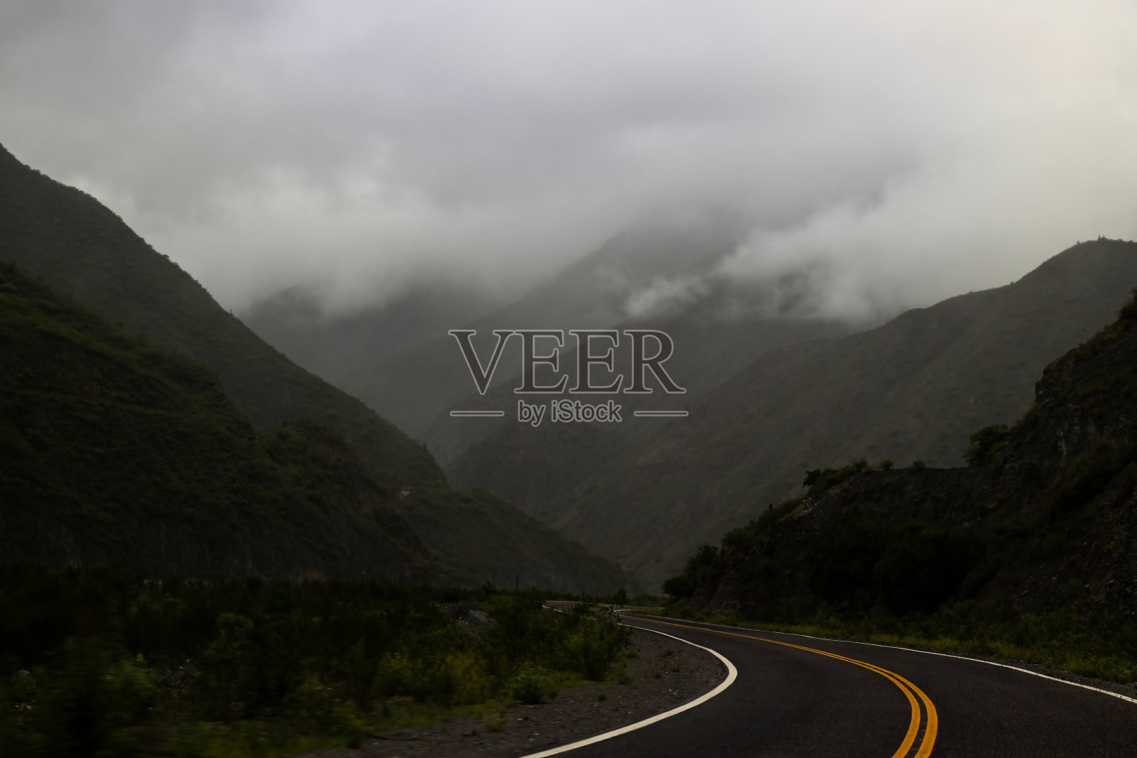 阿根廷萨尔塔，黄昏时分云层低低的山间公路照片摄影图片