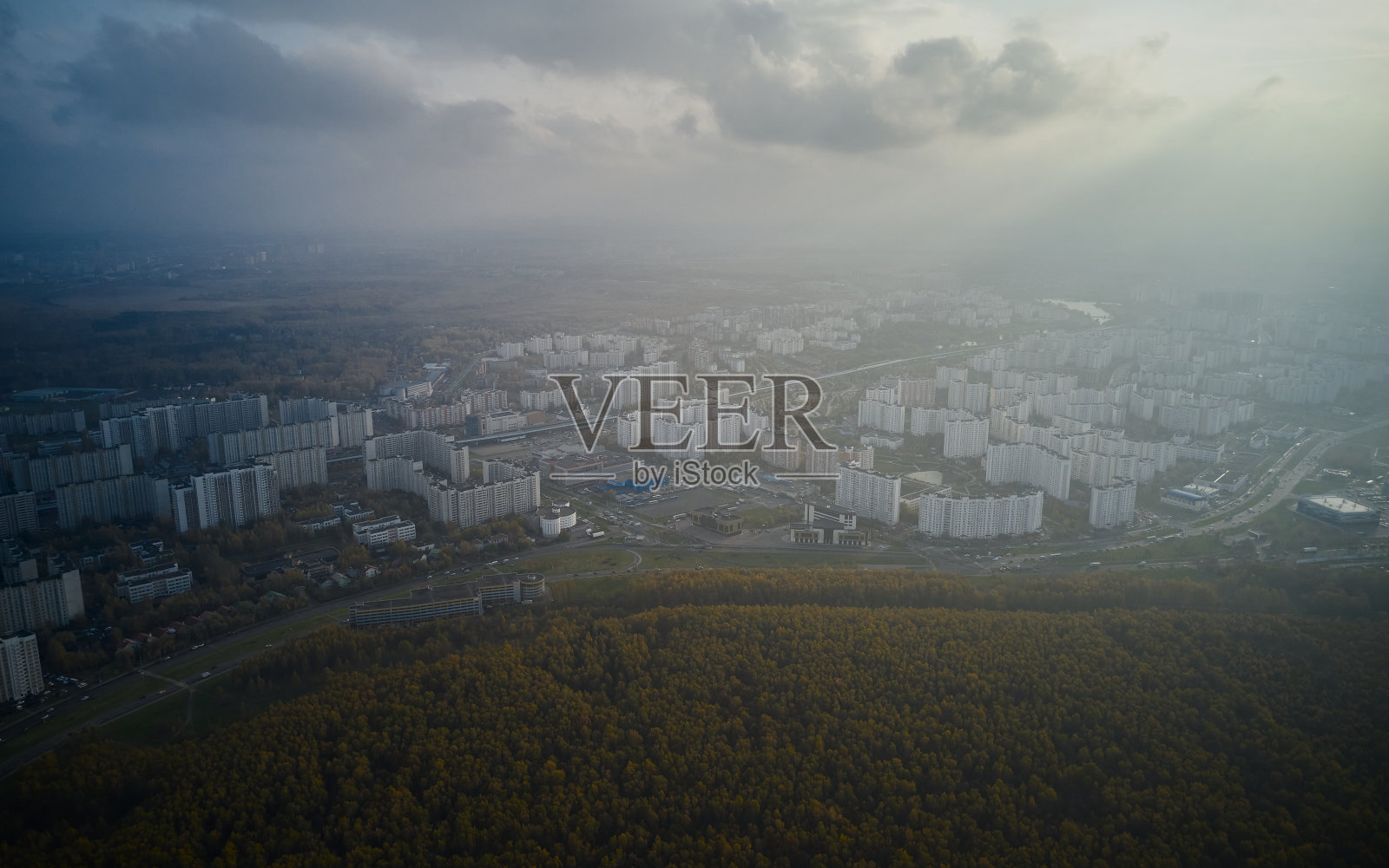 鸟瞰图中的小镇在雾中，前景是一片茂密的森林照片摄影图片