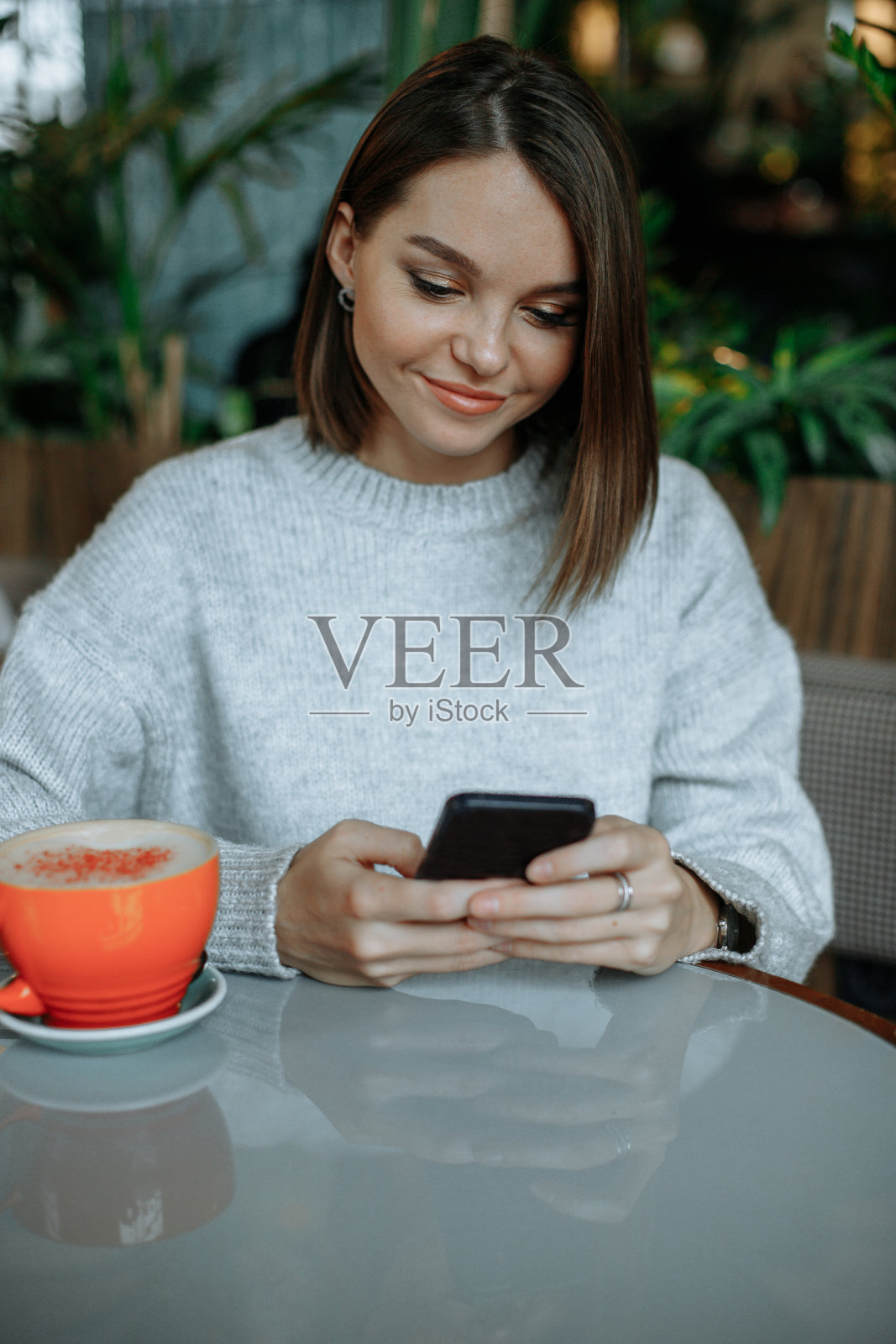 微笑的年轻黑发女子在咖啡馆使用智能手机照片摄影图片