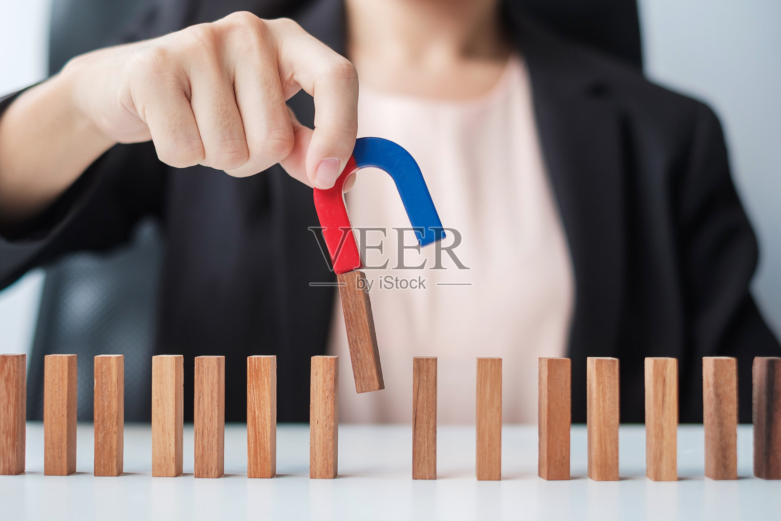 女商人手握磁铁，拉着男商人木雕从人群中走出。业务，人力资源管理，招聘，团队合作，战略，有毒的人和领导的概念照片摄影图片