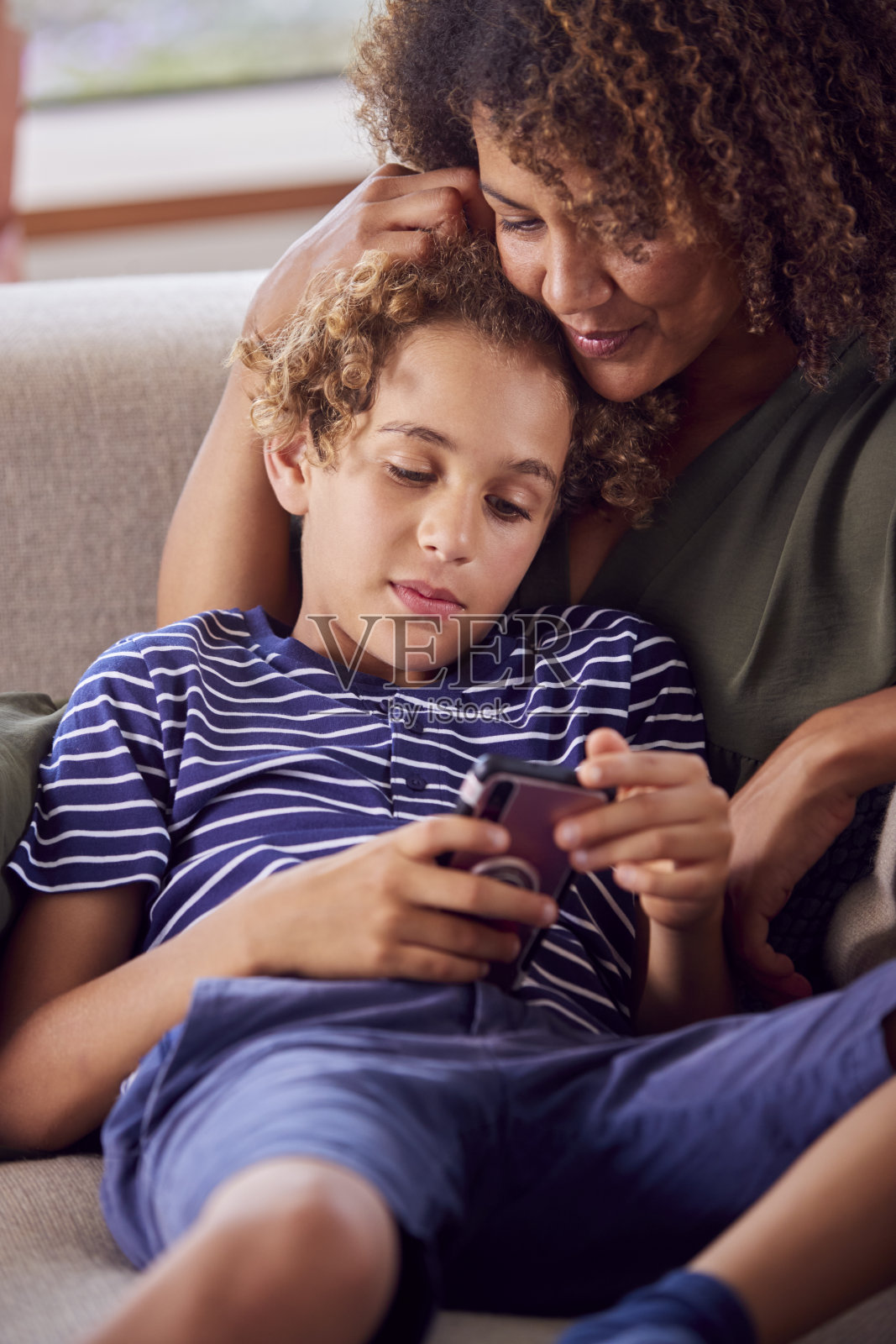 母子坐在沙发上玩手机游戏照片摄影图片