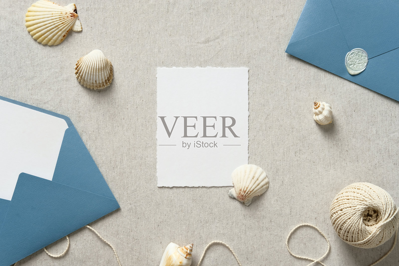 婚礼卡片模型与蓝色信封和米色背景上的海洋装饰。照片摄影图片