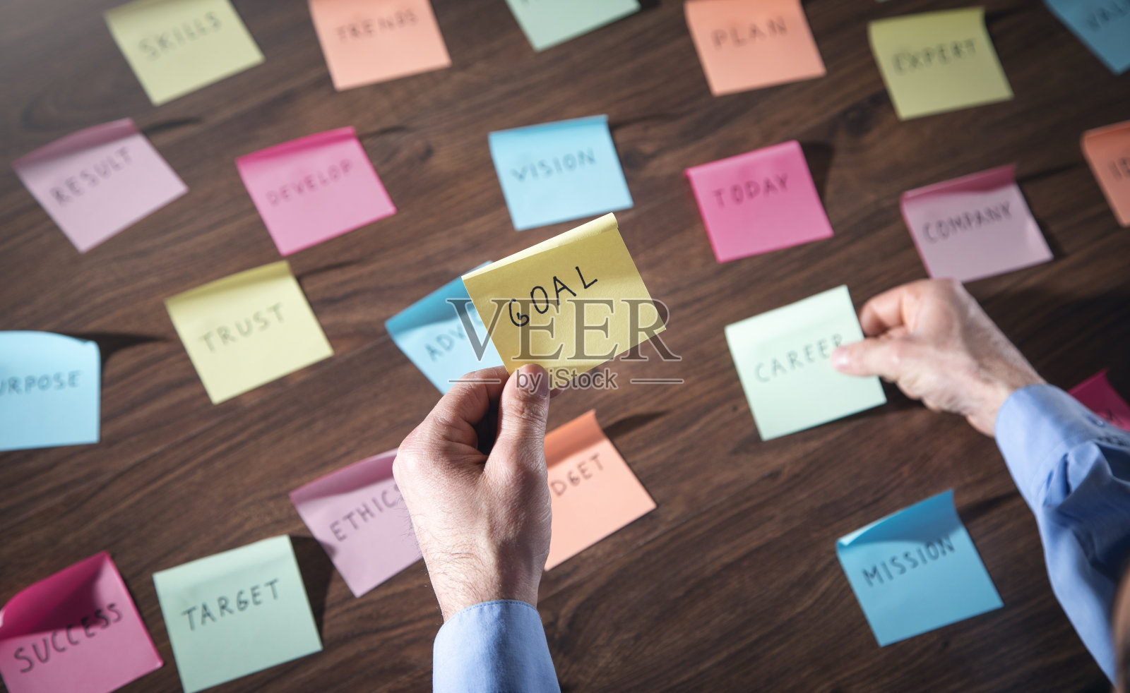 商人拿着便利贴上的目标字。在办公室工作照片摄影图片