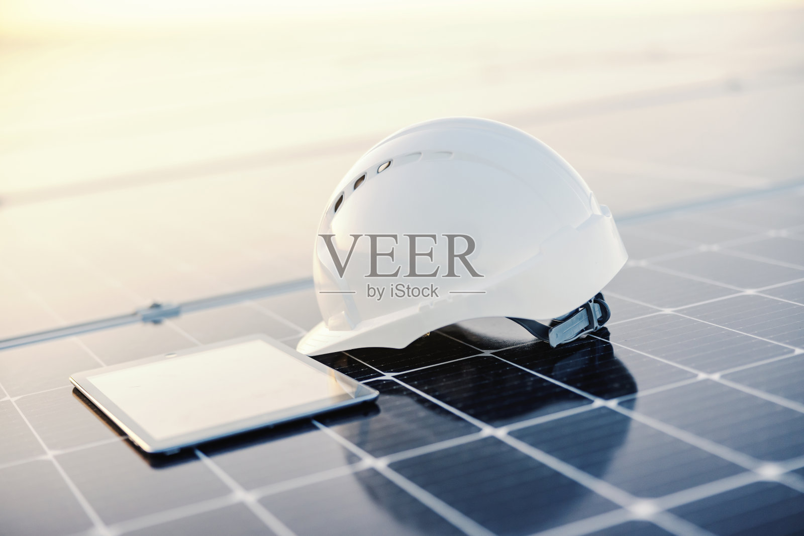 太阳能电池板上的头盔和平板电脑的特写。照片摄影图片