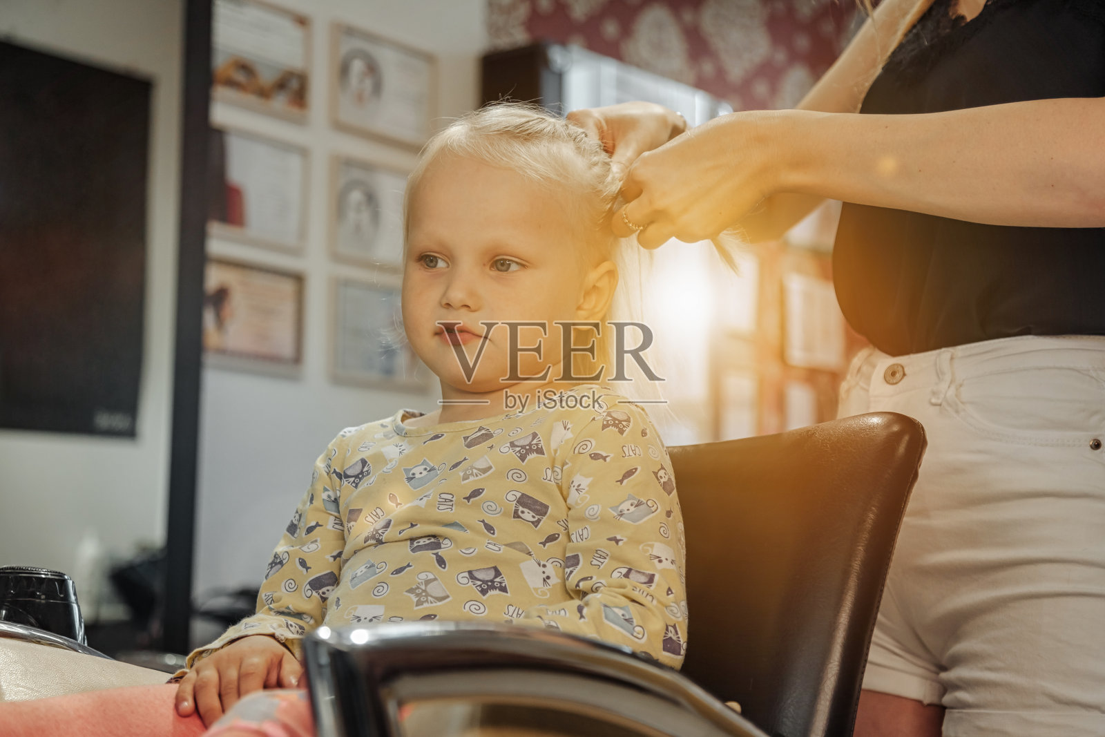 理发师为可爱的金发小女孩做时尚漂亮的发型照片摄影图片