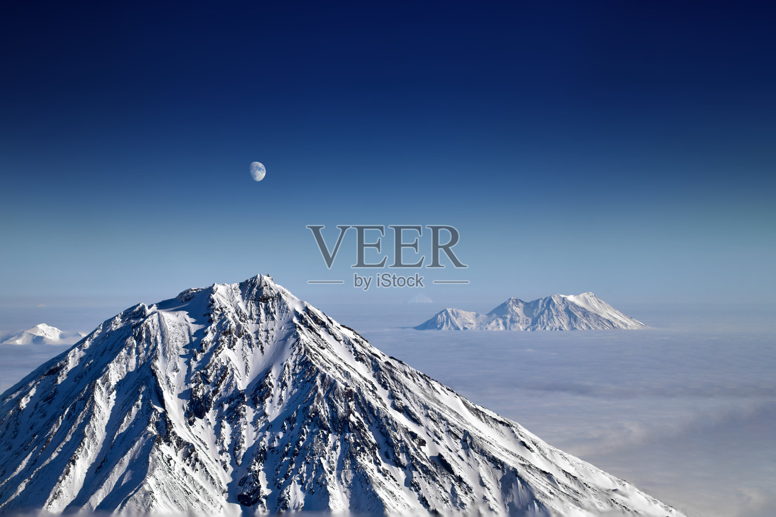 黎明时分的山景。山峰在厚厚的云层之上照片摄影图片